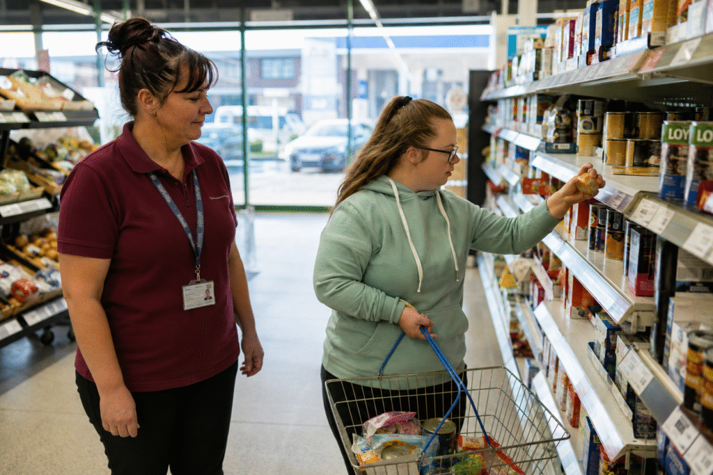 A support worker helping a young woman with a learning disability choose items during a supermarket shop